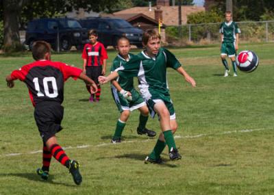 Ian De Graff moves the ball forward for the Vashon Cobras U 13 select soccer team.  Sam Briggs is defending in the background. Photo by Michael Elenko